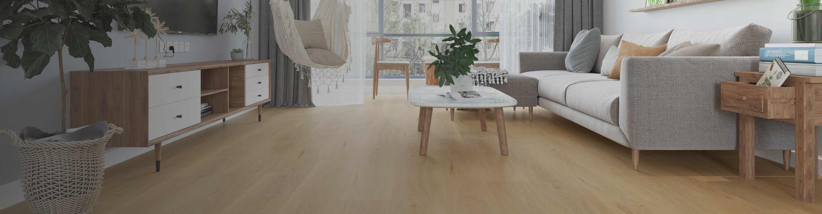 A bright living room with a light vinyl wood floor, a gray sectional sofa, a white coffee table, a wooden media console, and a hanging chair.